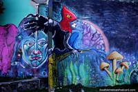 Indigenous face and a fantasy creature in a garden of mushrooms, street art in Villa La Angostura.