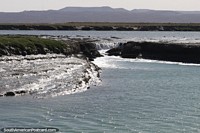 Rocks create a small waterfall on the coastline in Puerto San Julian.