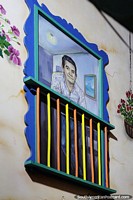 Window with mural on a building side in Guatape with flowers. Colombia, South America.