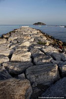 Rocks form a walkway out to the sea with El Morro Island in the distance in Santa Marta.
