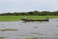 Men take out a long wooden river canoe in the marsh waters of Chimichagua.