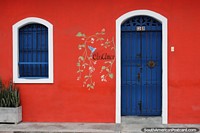 Frente de casa pintado de rojo con decoracin de pjaros y rboles en Honda - Casa Amor.